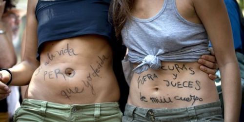 "Oui à la vie, mais je choisis" et "Prêtres et juges, hors de mon corps" peut-on lire sur le ventre de ces femmes qui manifestaient dimanche pour protester contre ce projet de réforme du droit à l'avortement. | AFP/DANI POZO