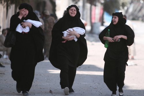 Women carry newborn babies while reacting after they were evacuated by the Syria Democratic Forces (SDF) fighters from an Islamic State-controlled neighbourhood of Manbij